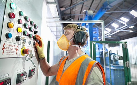 man in mask and gloves checking a control board